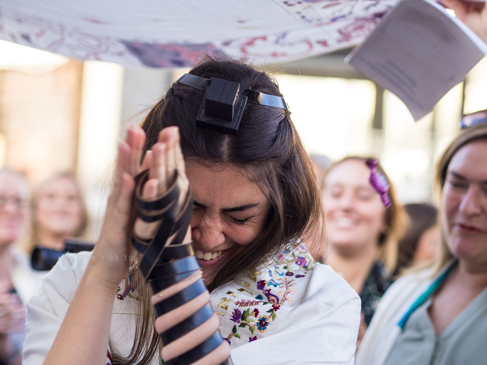 A woman with brown hair and tefillin praying