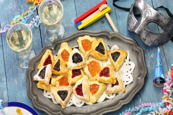 Purim spread featuring hamantaschen party favors and two glasses of white wine